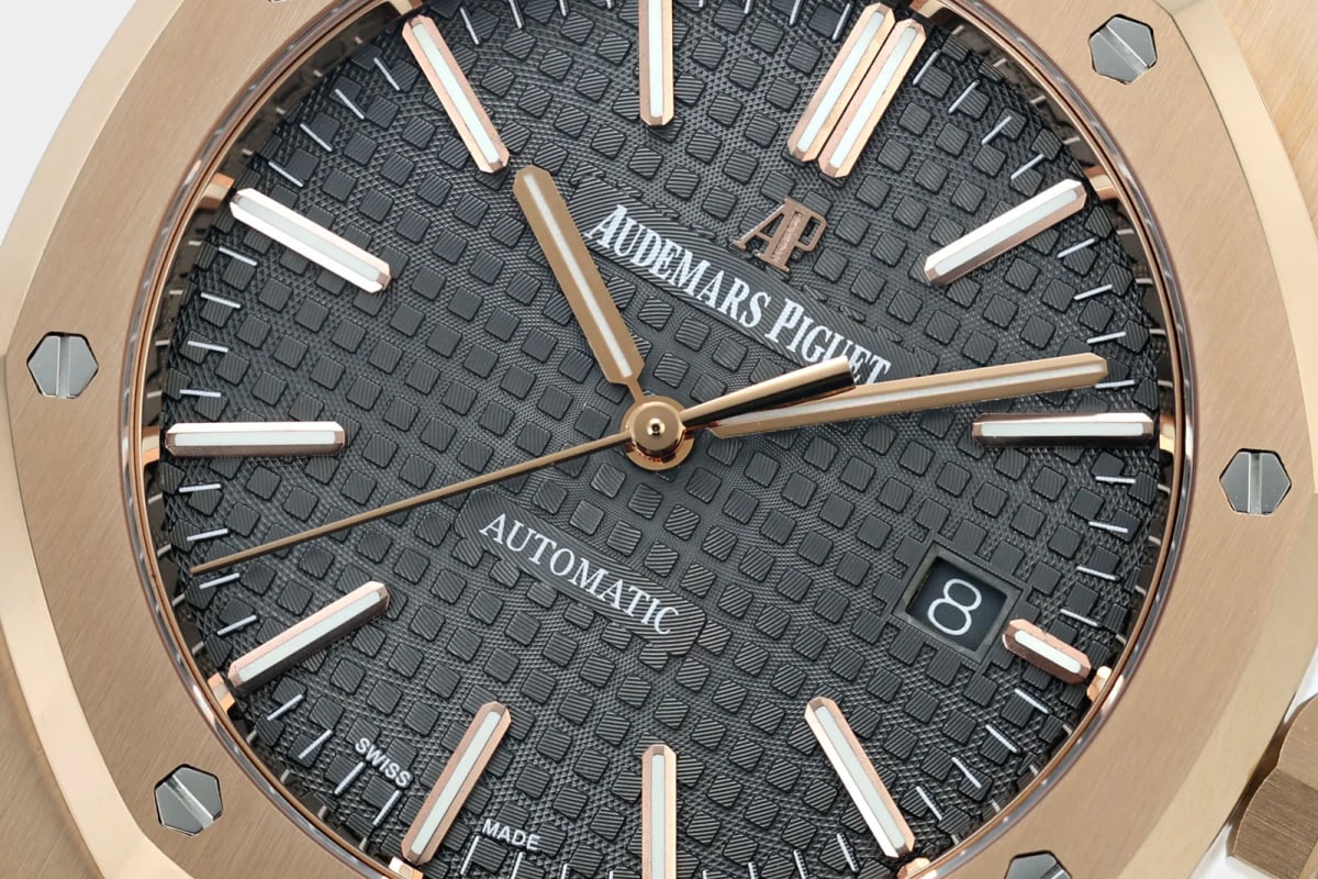 Dial close-up: the AP monogram and AUDEMARS PIGUET print, the squared Grande Tapisserie texture, applied rose-gold baton markers and hands, the date window and the SWISS MADE print at the lower edge