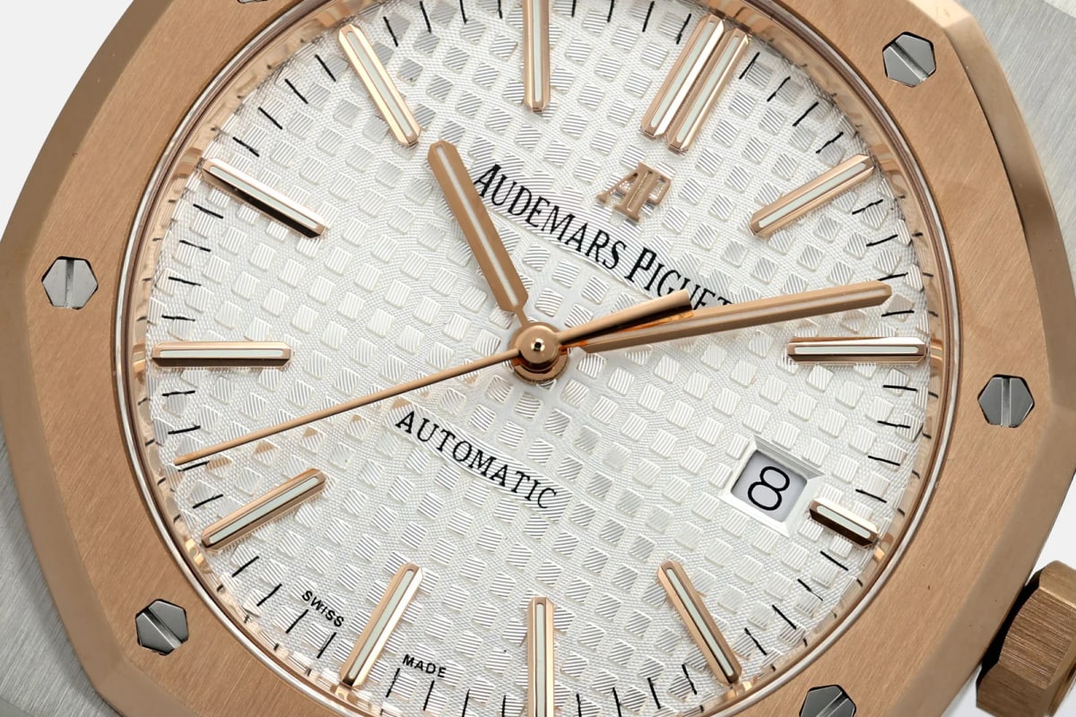 Dial close-up showing the Audemars Piguet and Automatic lettering, the raised squares of the pattern, applied baton markers, slim hands, the date window at three and the bezel screw heads