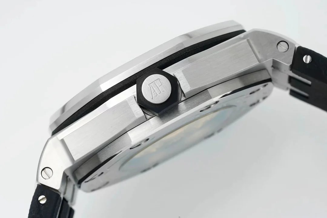 Detail of the case flank and crown: the octagonal crown with the monogram on its face, the brushed case edge, a screw head where the strap meets the lug and the black strap leading away