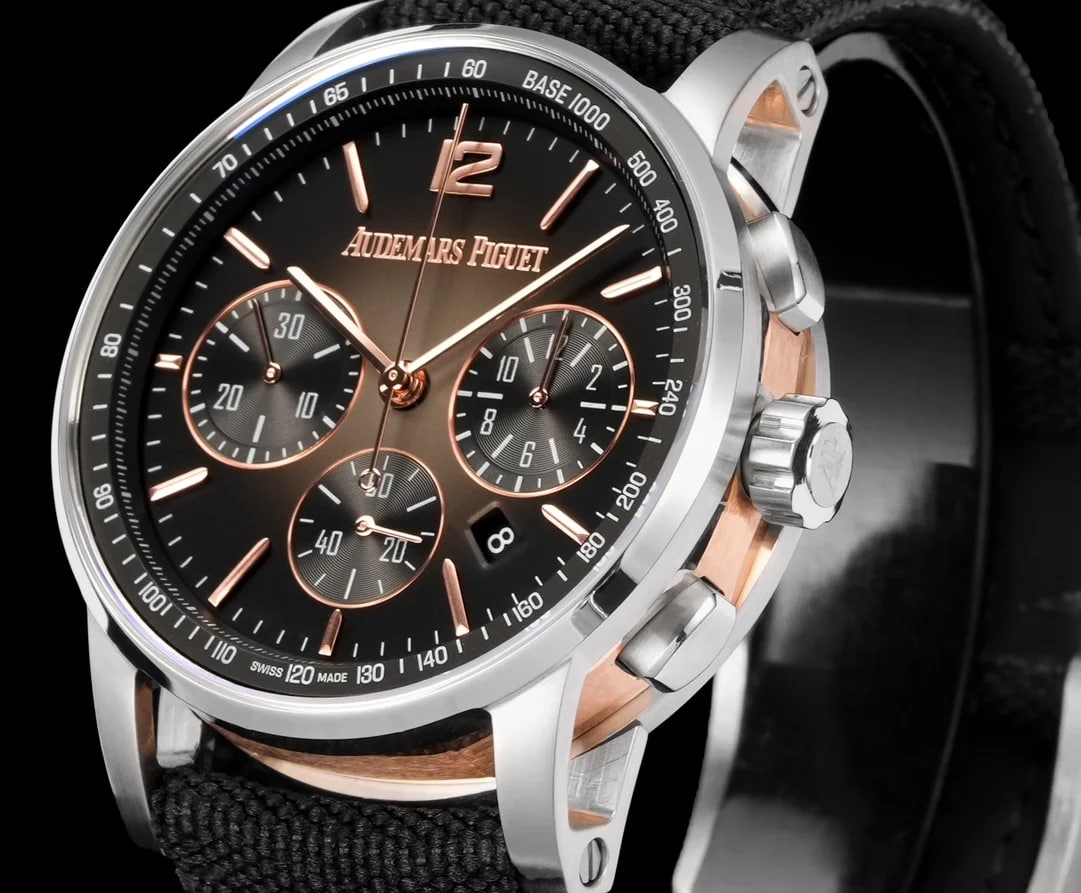 Dial close-up with the AUDEMARS PIGUET lettering above the centre, the applied numeral twelve and baton markers around the dial, the three counters with their printed scales, the pale minute track and the date aperture in the lower right