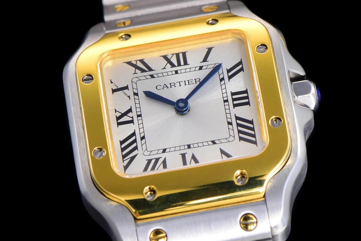 Dial close-up showing the CARTIER lettering above the centre, the black Roman numerals inside the printed square minute track, the two blue hands and the screws set into the gold-toned bezel