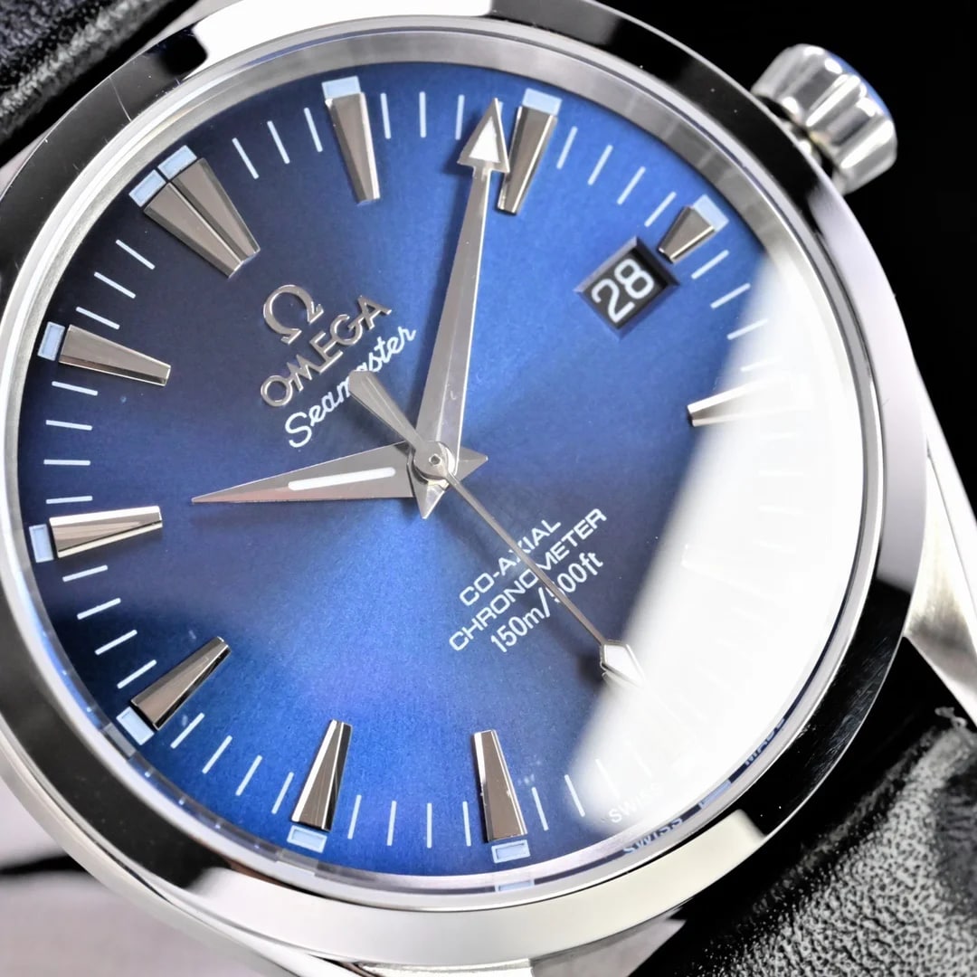 Close detail of the blue dial with the brand name and the Seamaster script above the centre, the printed block under the hands naming the escapement and the chronometer wording, and the date aperture showing two digits.