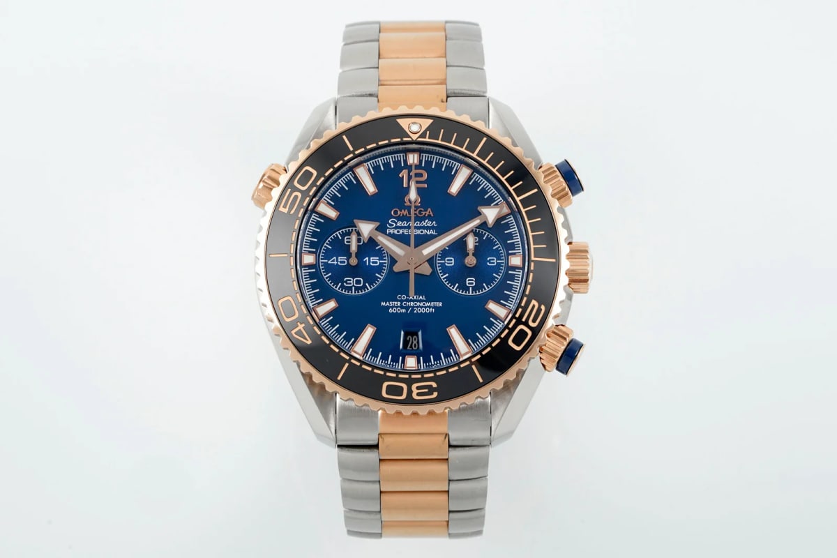 Blue ceramic dial straight on with applied markers, two counters either side of the centre, the date at six, a dark bezel with a gold-toned diving scale and a two-tone bracelet below