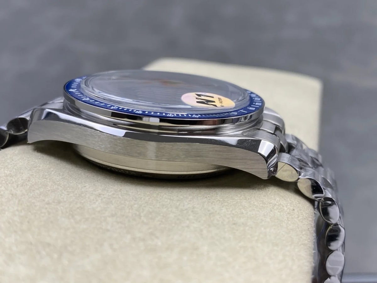 Detail of the case flank with its crown and two pushers, the sticker on the glass, the bezel edge seen from the side and the bracelet folded with its clasp