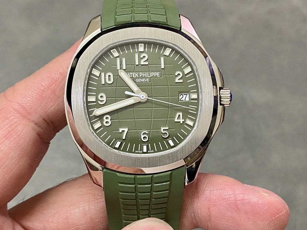 Khaki green dial straight on with an embossed grid pattern, applied Arabic numerals and baton markers, the date window at three and a green patterned strap below the white-metal case