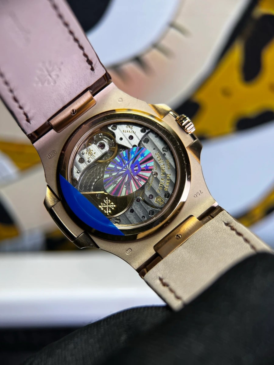 Case back detail with the sapphire back showing the winding weight and plates of the movement, lettering on the movement beside it, and the brown strap folded behind the case