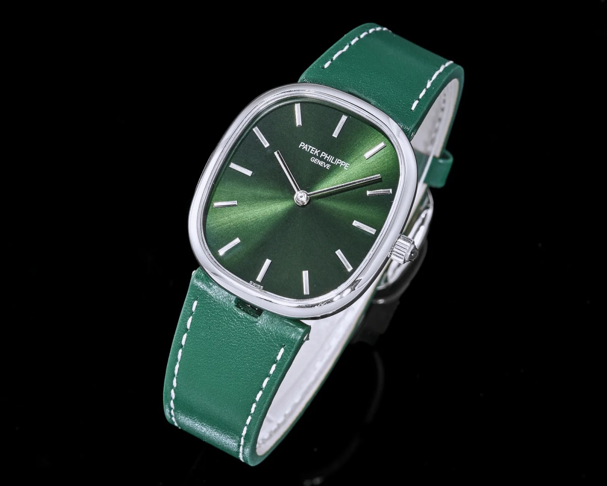 Angled three-quarter view of the watch on its green stitched strap, the sunburst rays on the dial fanning toward the rim and the ribbed crown standing out on the right flank of the polished case