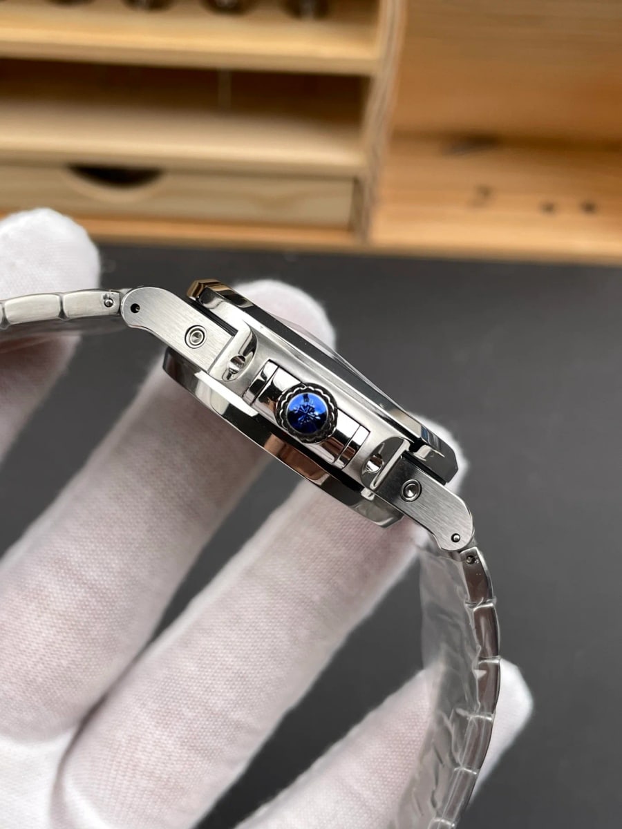 Close-up of the closed folding clasp on the bracelet, held in a gloved hand, showing how the links fold back toward the case