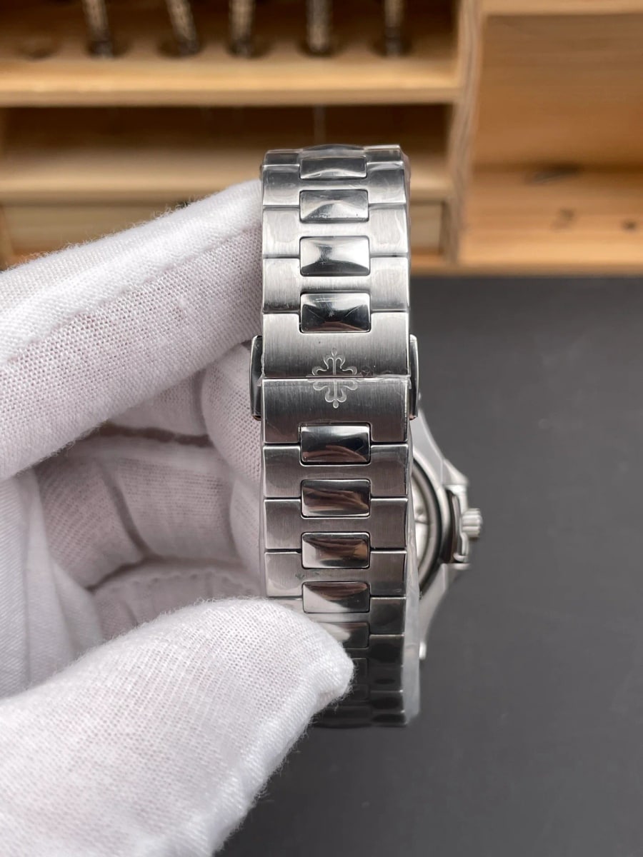 View of the case angled from the side and slightly behind, showing the shallow profile, the crown at the right and the folded bracelet running out of frame