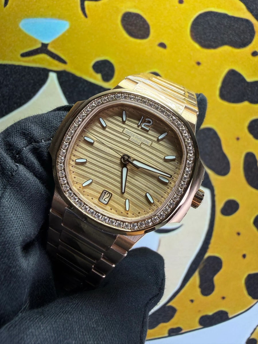 Angled view from above and to the side, the wave pattern on the golden brown dial reading obliquely under the stone-set bezel, with the rose-gold links running down from the case