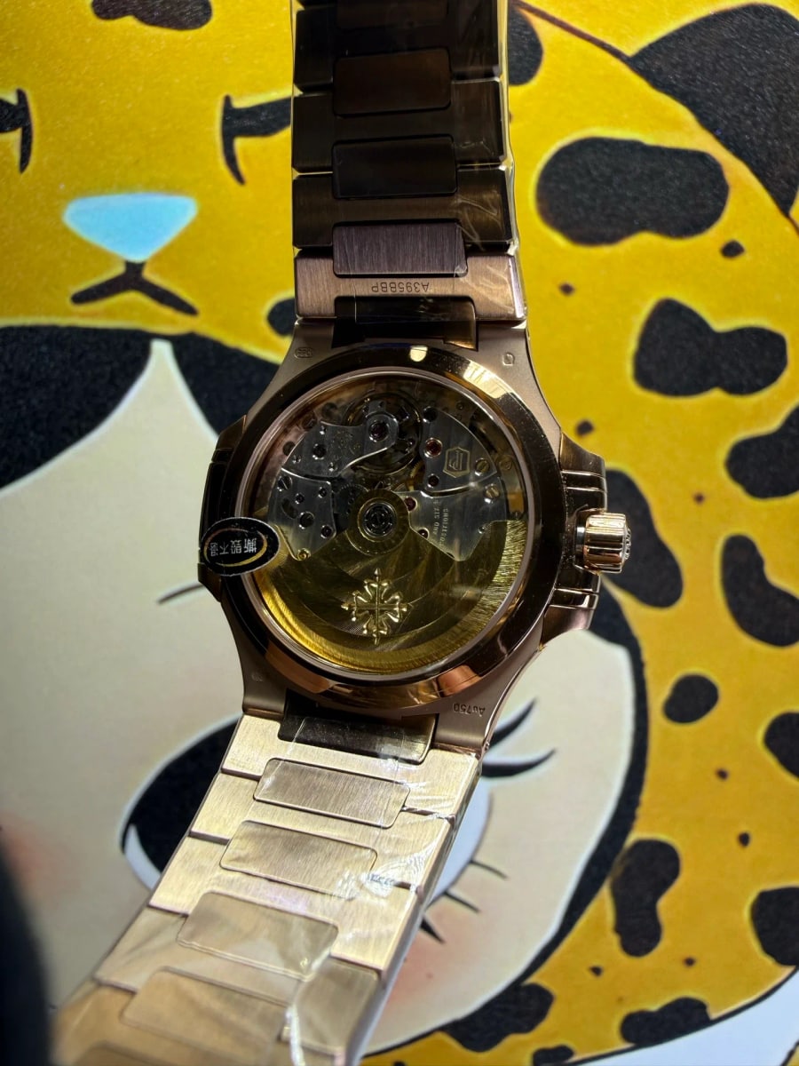 Case back detail with the movement visible through the sapphire back in the gold-tone case, its bridges and screw heads showing, and the bracelet folded back beside it