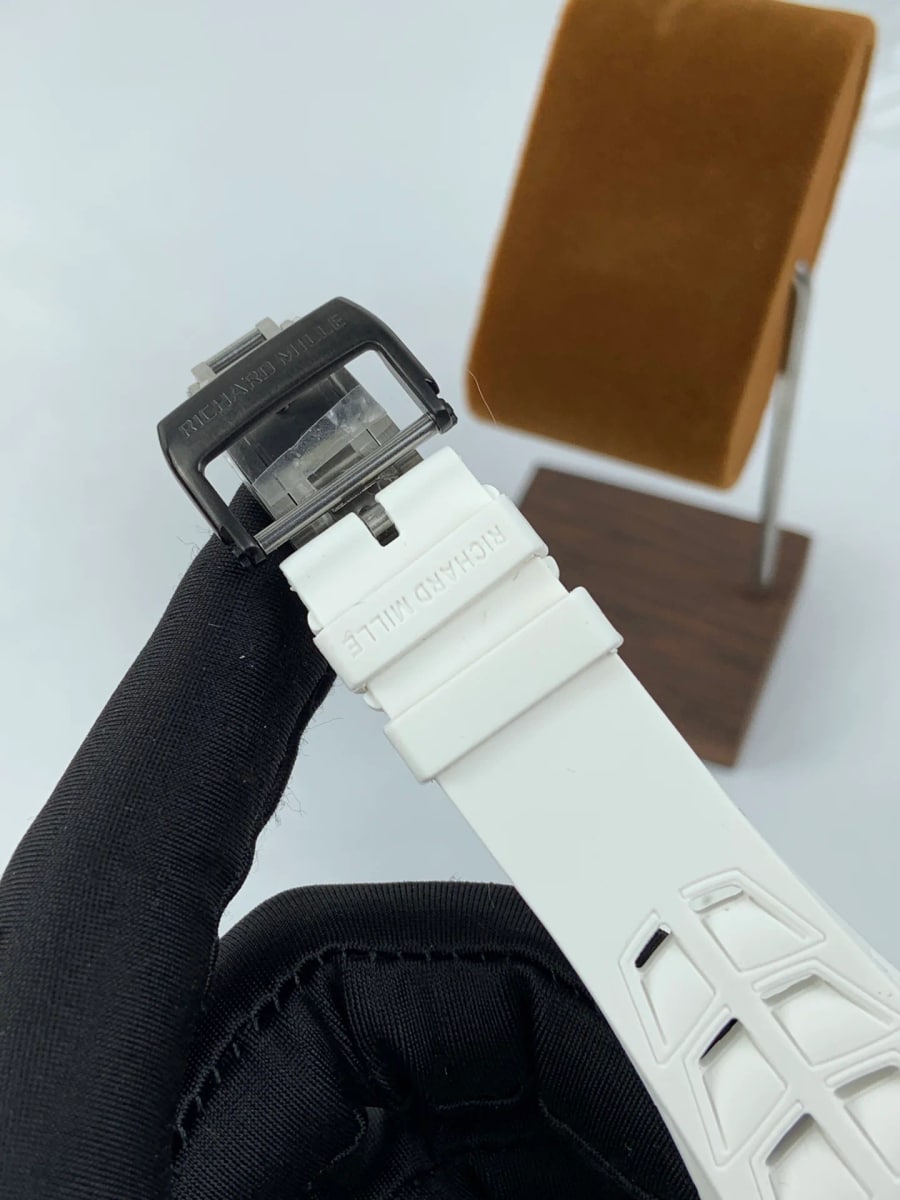 Strap and clasp detail with the white strap and the folding clasp in focus, the brand name embossed on both and the moulded strap pattern running out of frame