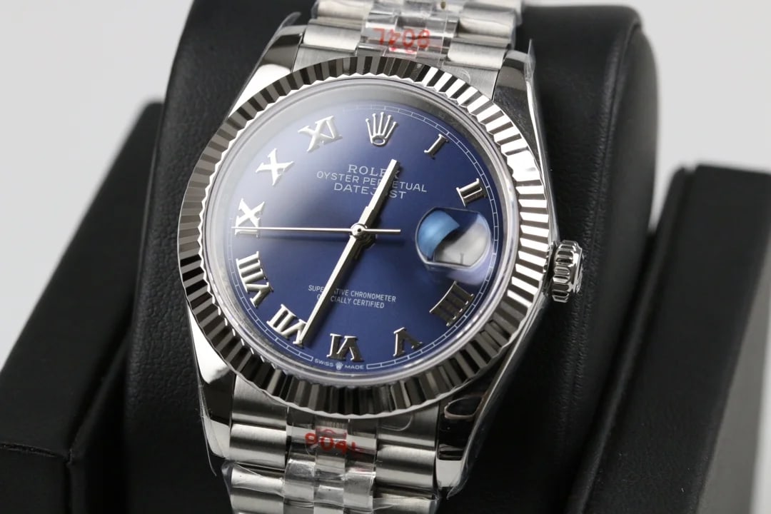Three-quarter view of the fluted bezel around the blue dial, with the applied Roman numerals reading in sequence and the bracelet turned towards the camera