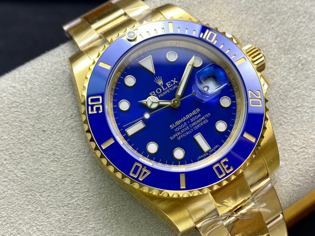 Three-quarter view of the blue bezel insert reading 50, 40, 30, 20 and 10 in gold, with the magnifier over the date and the gold bracelet below the case