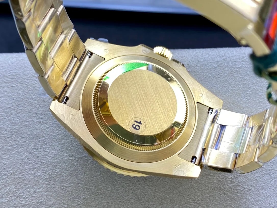 Case back detail on the gold case, seen with the bracelet folded underneath and the protective sticker still in place over the back