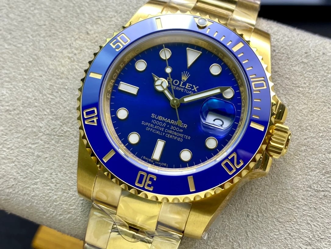 Dial and bracelet view of the gold Submariner Date, showing the blue bezel numerals, the magnifier over the date and the three-link bracelet