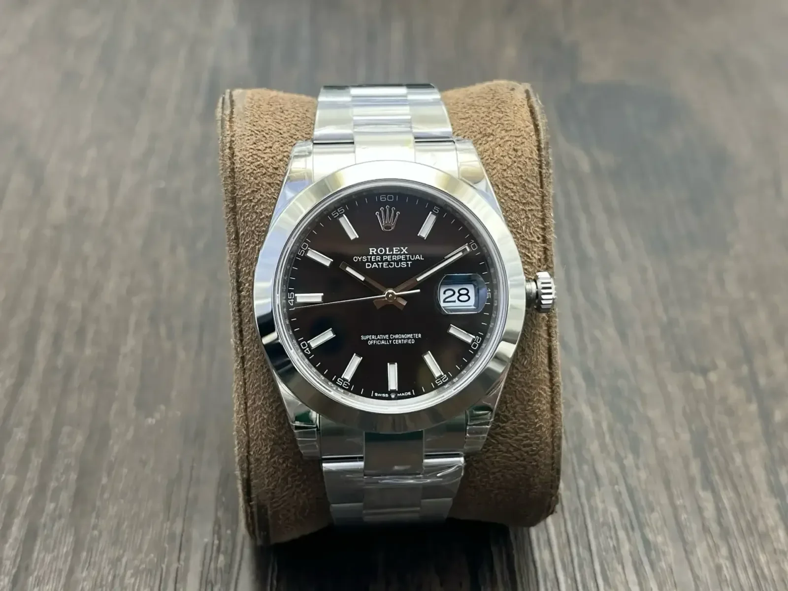 Black dial straight on in the steel case, with the smooth polished bezel, applied markers and the date under its magnifier above the three-link bracelet