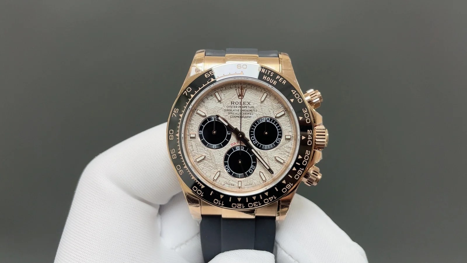 Meteorite and black dial straight on in the warm-gold case, with the full tachymeter scale reading around the black bezel and the black strap below