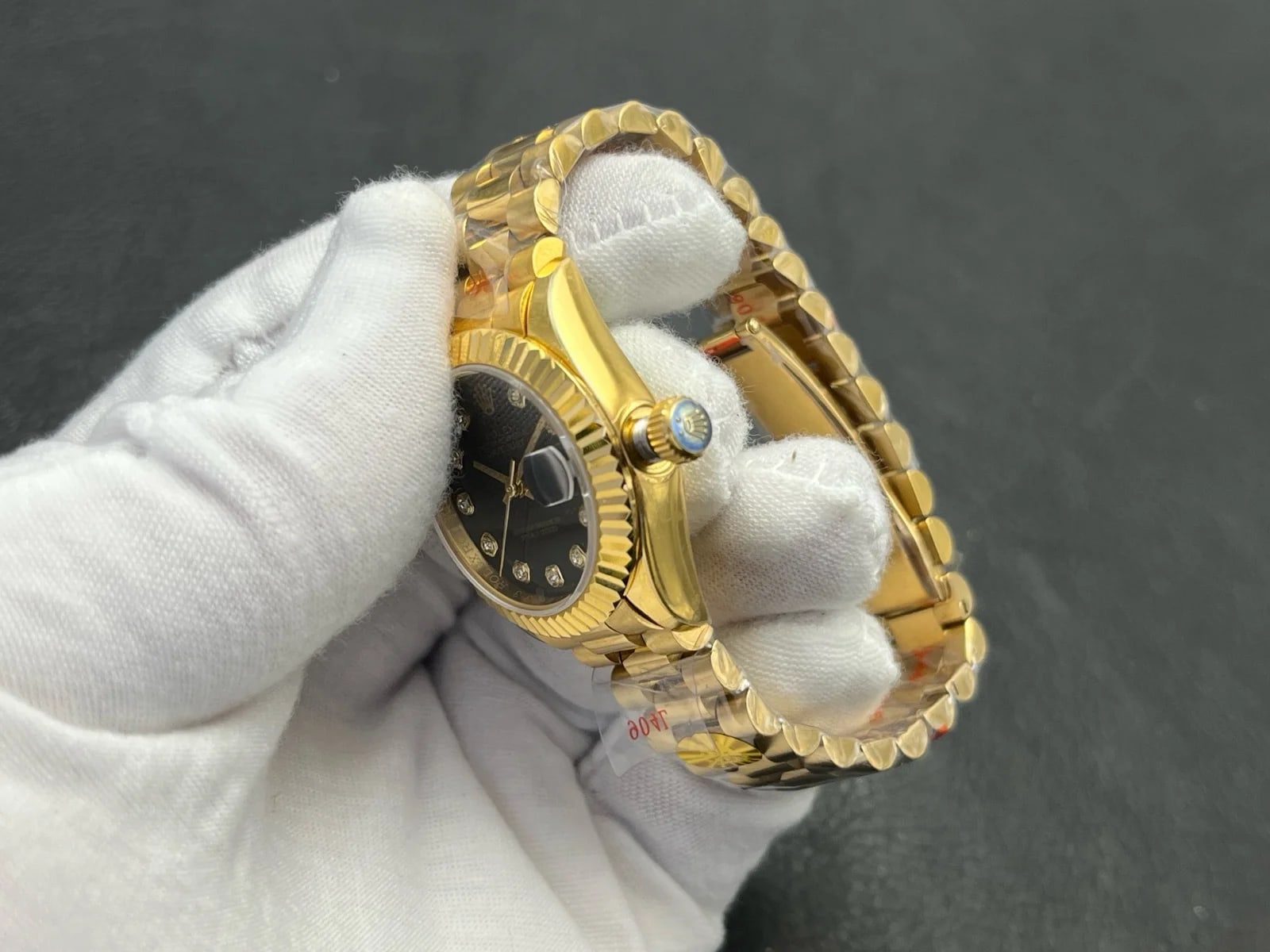 Bezel and crown close-up with the fluting in the foreground, the winding crown beside the case and the dial edge running behind it