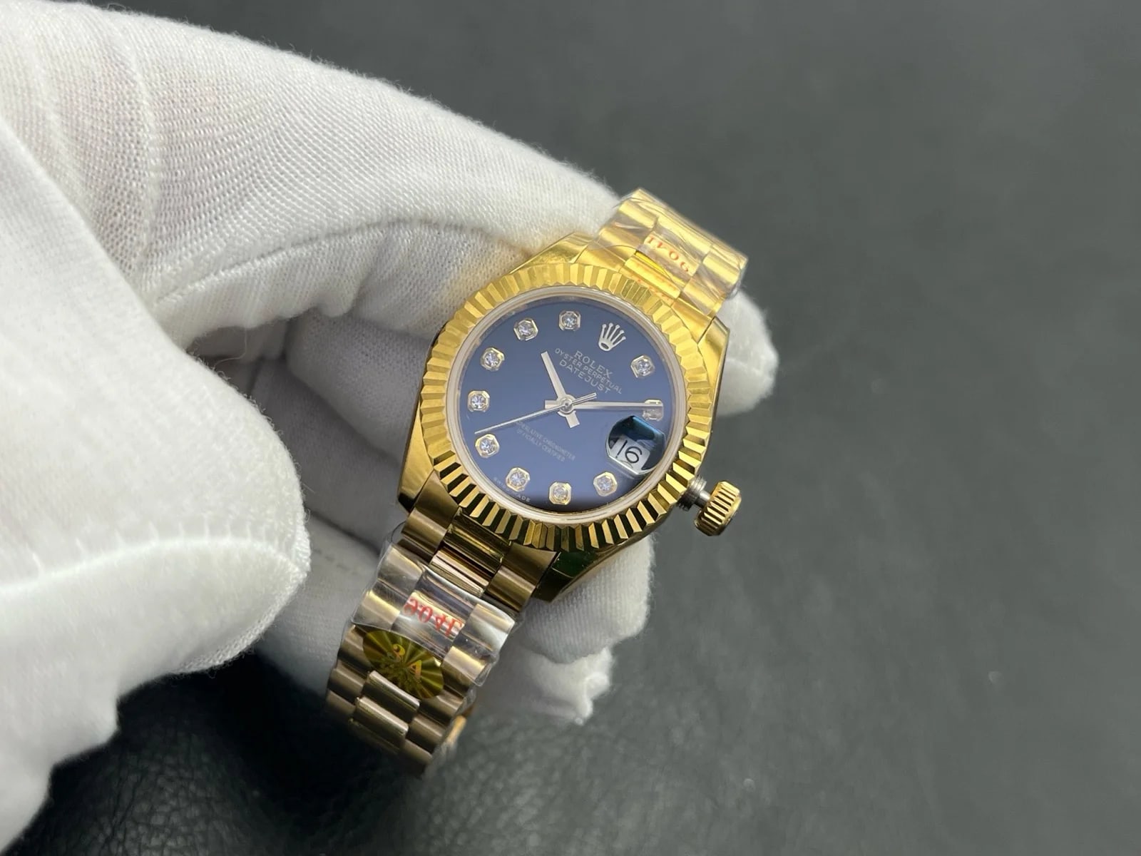 Three-quarter view showing the fluted bezel catching the light above the dark dial, with the gold bracelet turned towards the camera