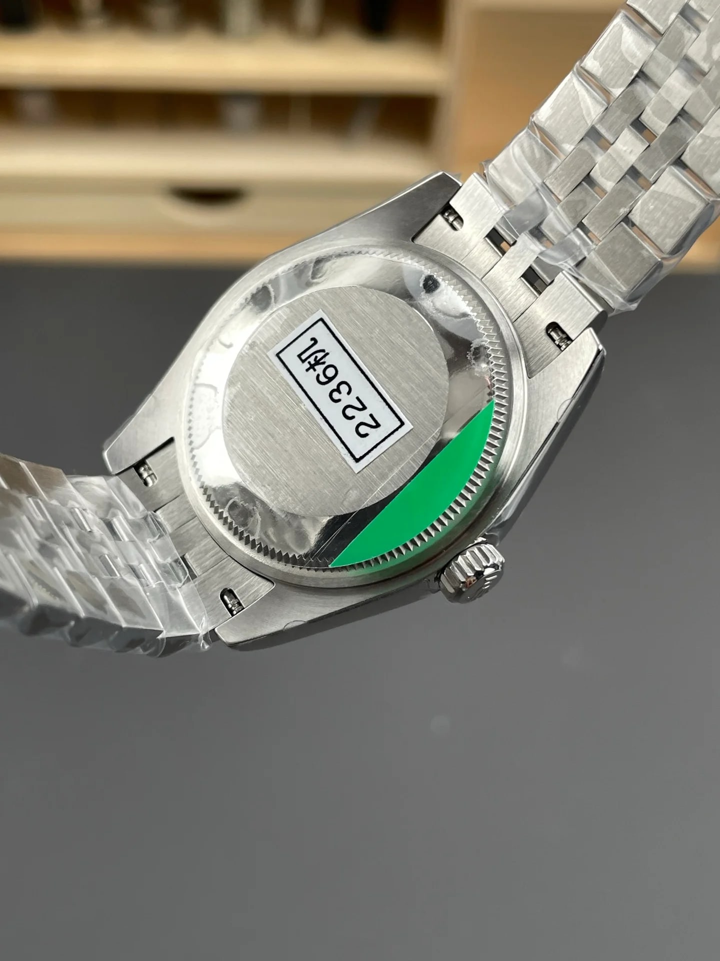 Case back detail of the silver-tone back with its protective sticker, the stone-set bezel edge visible around the case and the case flank beside the crown