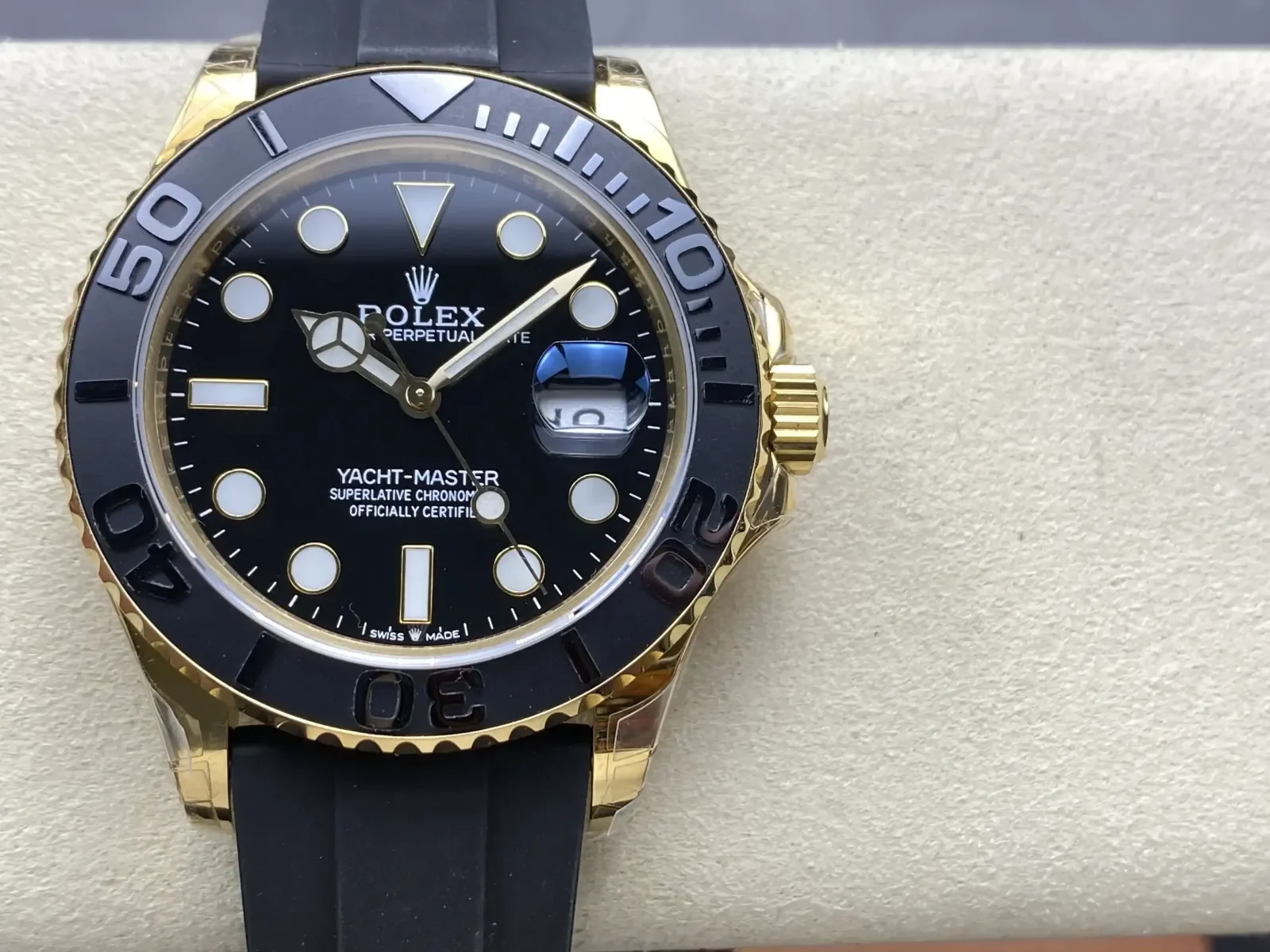 Black dial straight on in the gold case, with raised polished numerals on the black bezel, the date under its magnifier and the black rubber strap