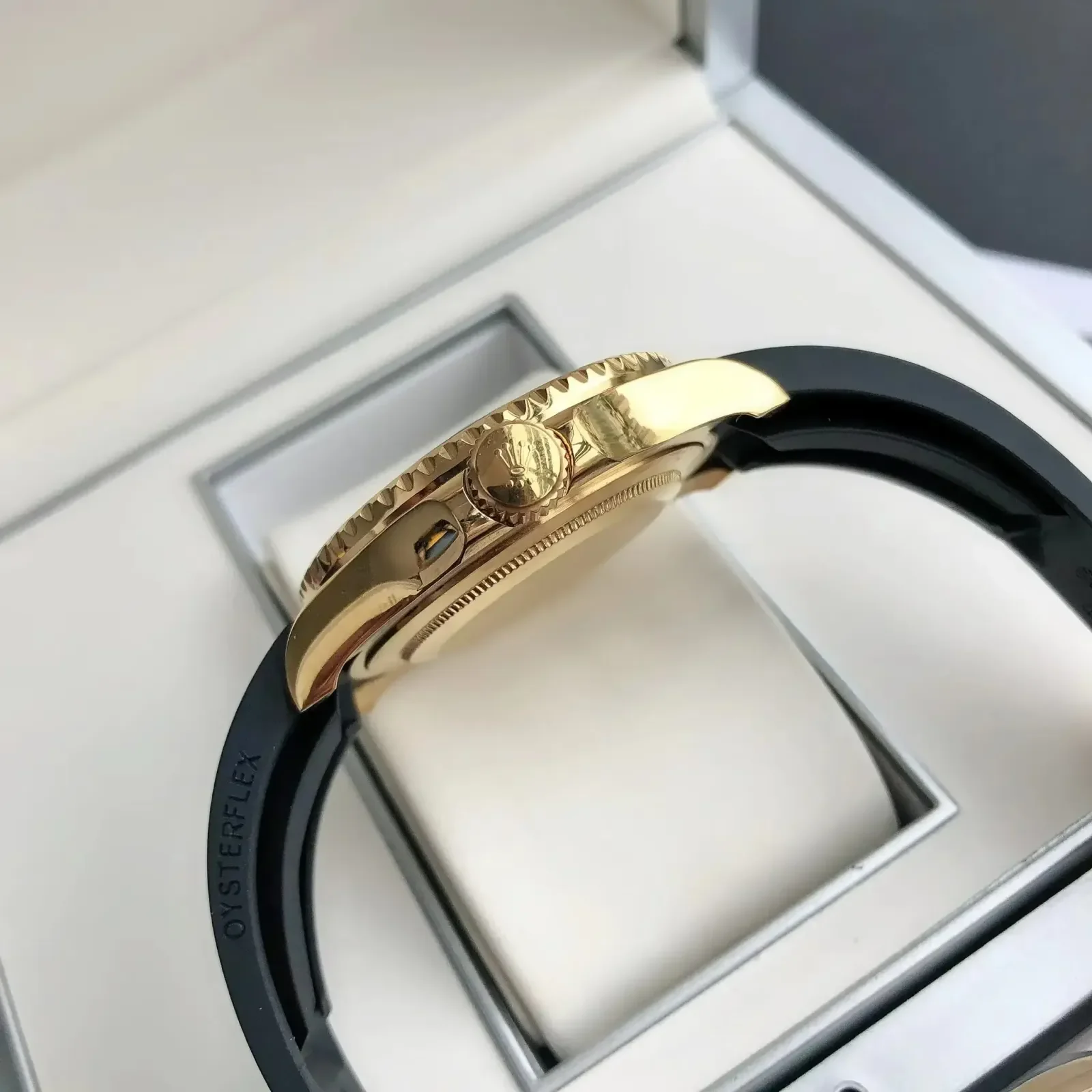 Clasp and case side detail, with the gold case flank, the bezel edge and the folding clasp closed across the black strap