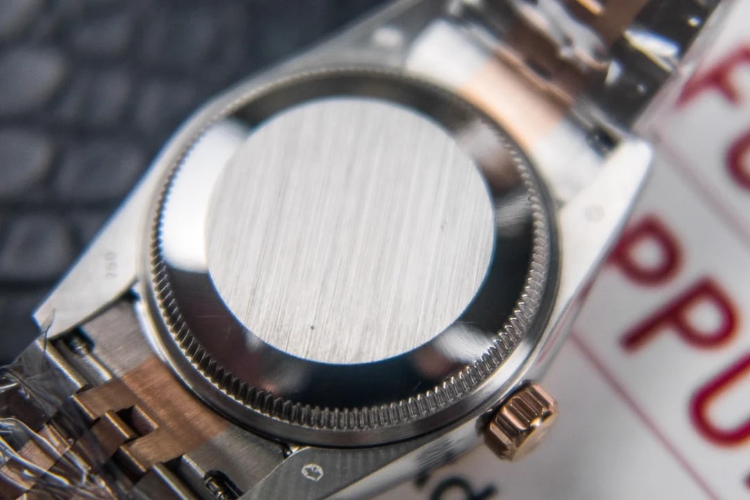 Case back detail showing the steel back against the rose-gold sides, with the bracelet end links and the case flank in view