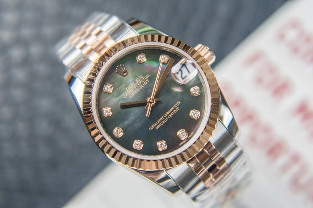 Three-quarter view of the rose-gold fluted bezel above the dial, with the magnifier over the date and the bracelet curving away from the case