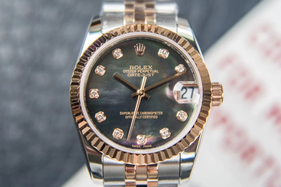 Mother-of-pearl dial straight on with stone markers, a fluted rose-gold bezel, the date under its magnifier and the two-tone five-link bracelet