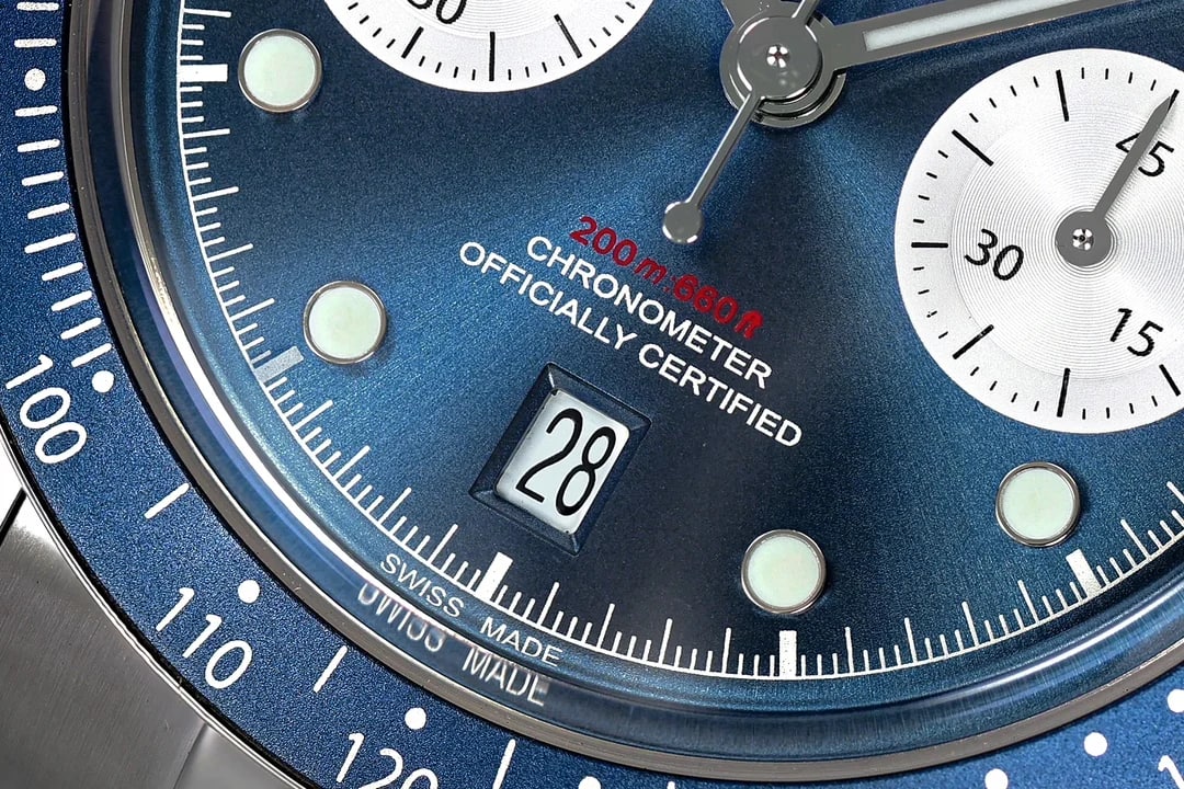 Close-up of the lower dial: the brand lettering above centre, the block of printed text beneath it, the two-digit date window at six o'clock and the printed scales inside both silver counters