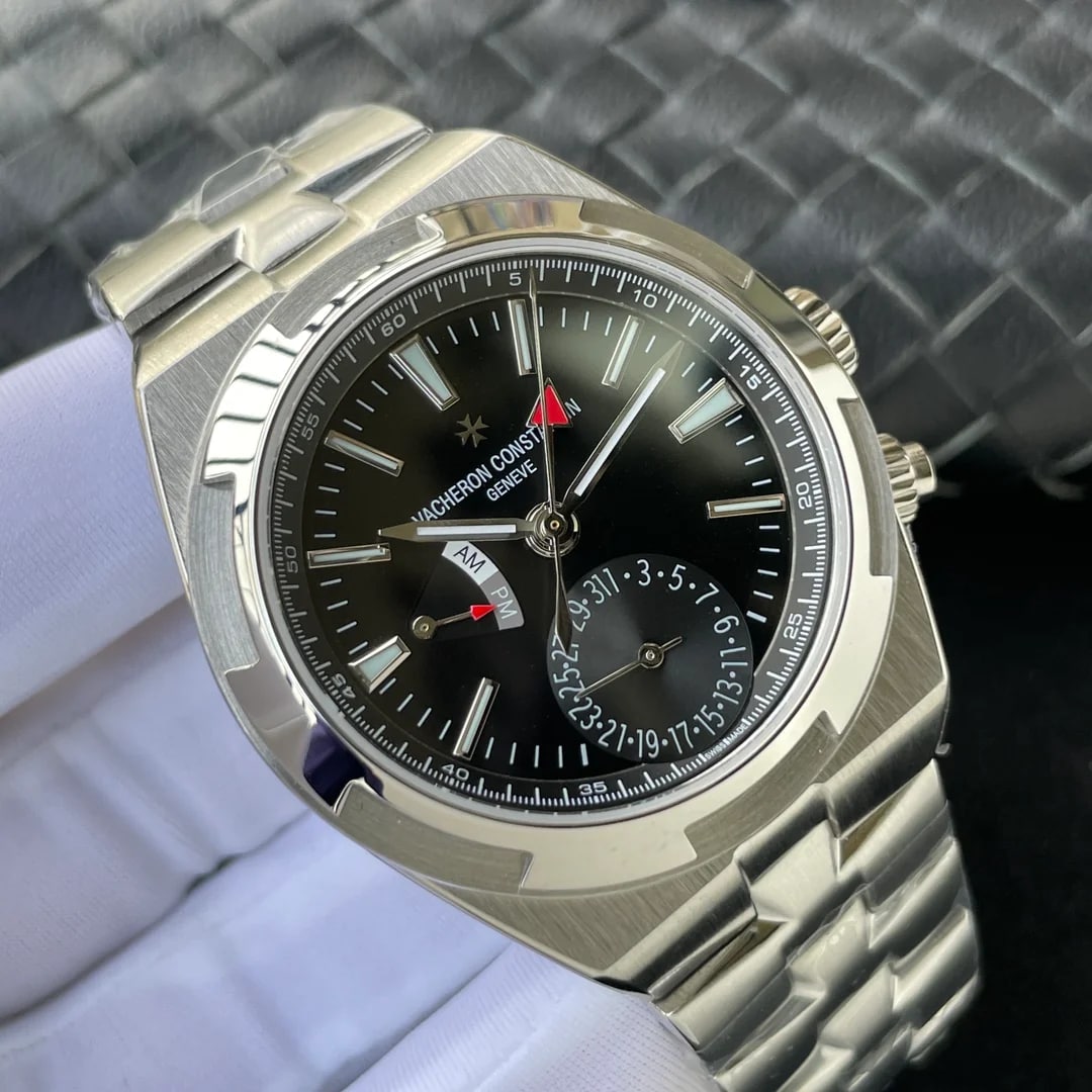 Angled view of the black dial and the multi-link bracelet, with the printed minutes track, the baton markers and the AM over PM scale near nine in view